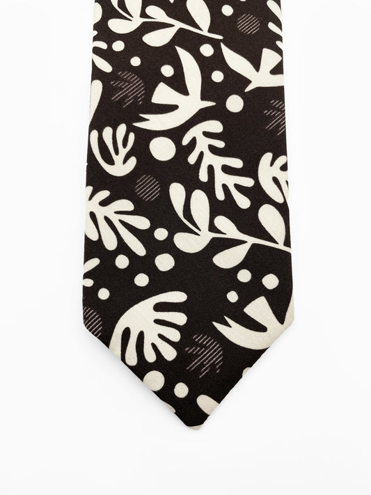 A cotton necktie with cream-colored birds and abstract shapes.
