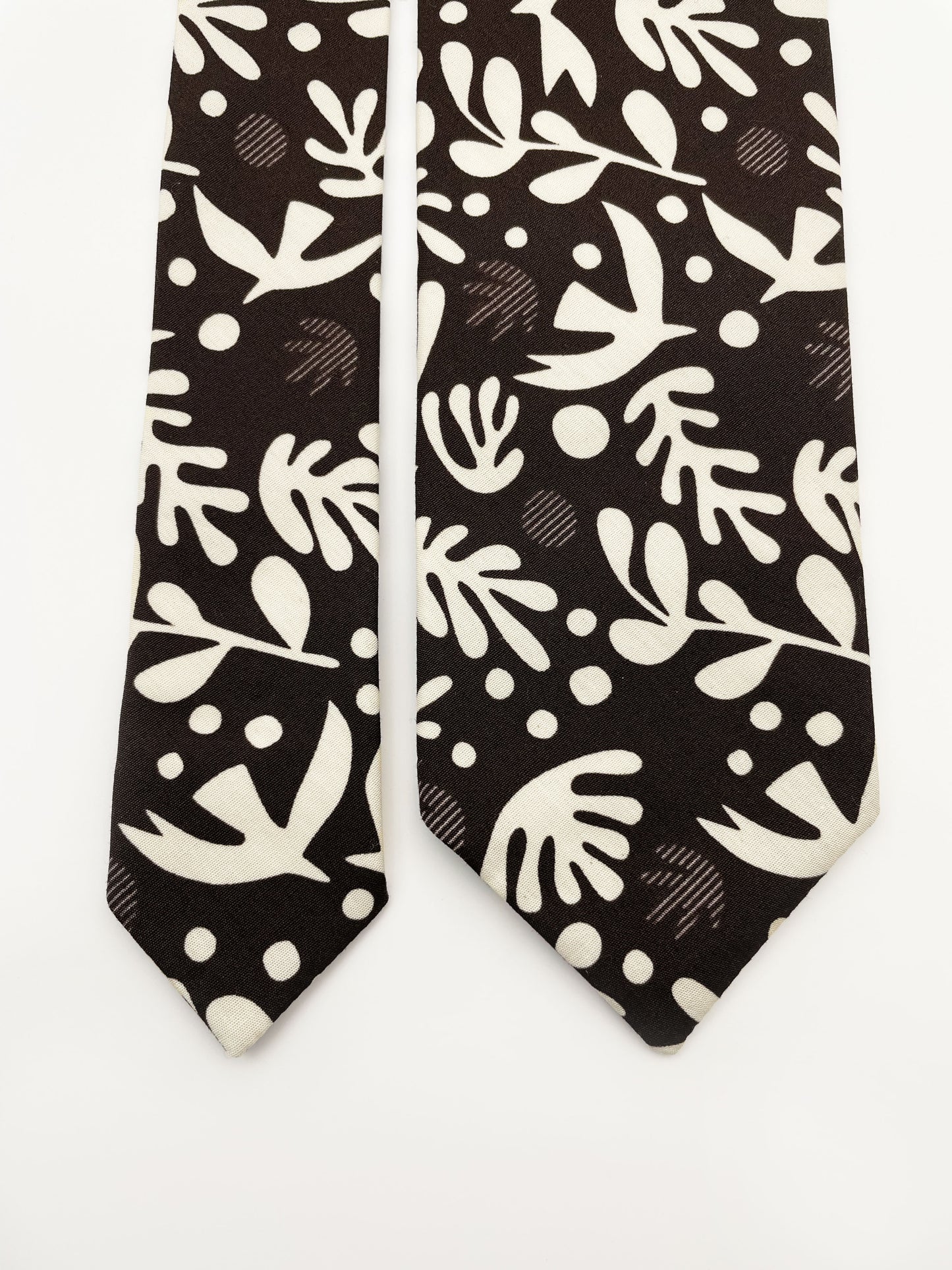 A cotton necktie with cream-colored birds and abstract shapes.