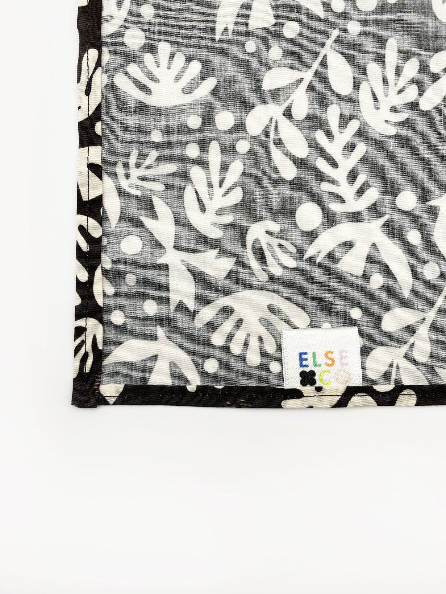 A cotton handmade pocket square with cream-colored birds and abstract shapes.