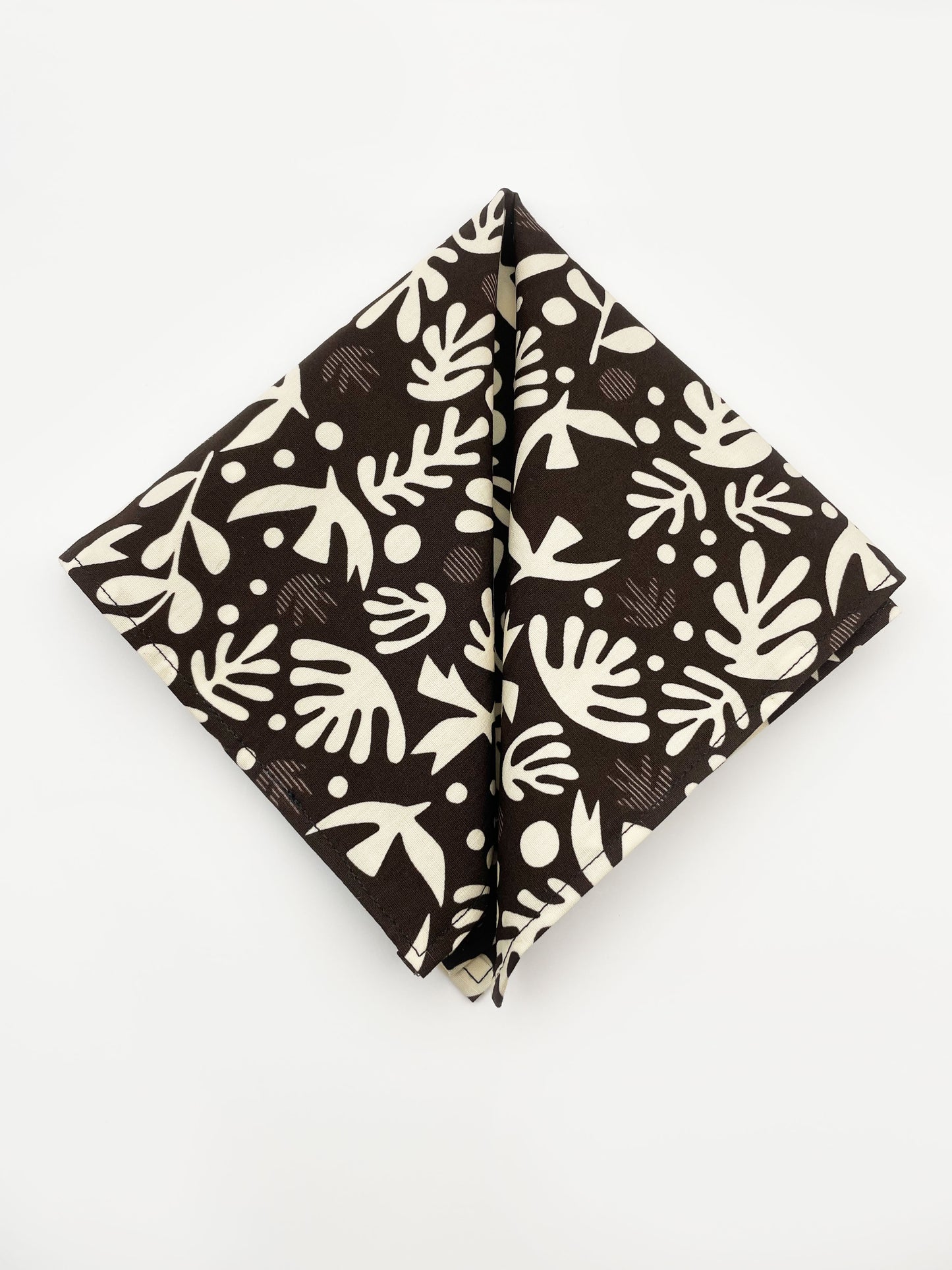 A cotton handmade pocket square with cream-colored birds and abstract shapes.