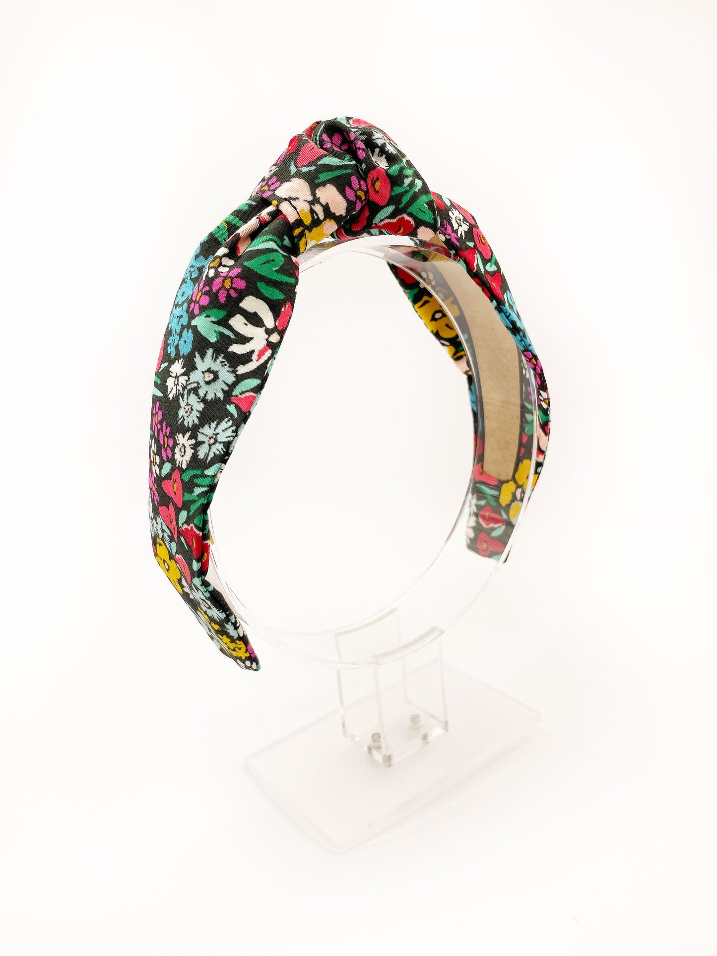 A black handmade knotted headband with a colorful floral print.