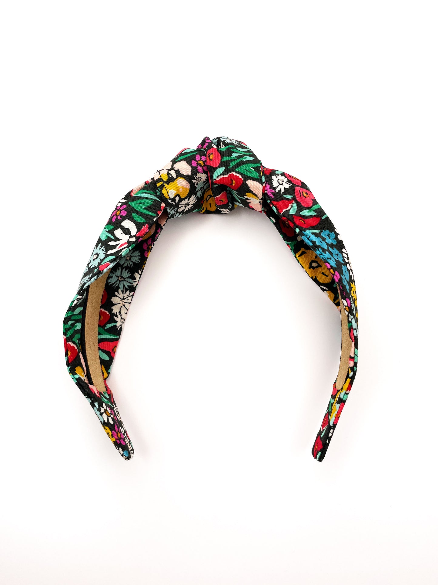 A black handmade knotted headband with a colorful floral print.