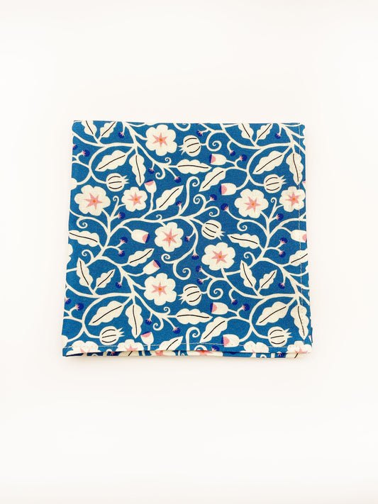 A blue pocket square with white flowers that have pink centers.
