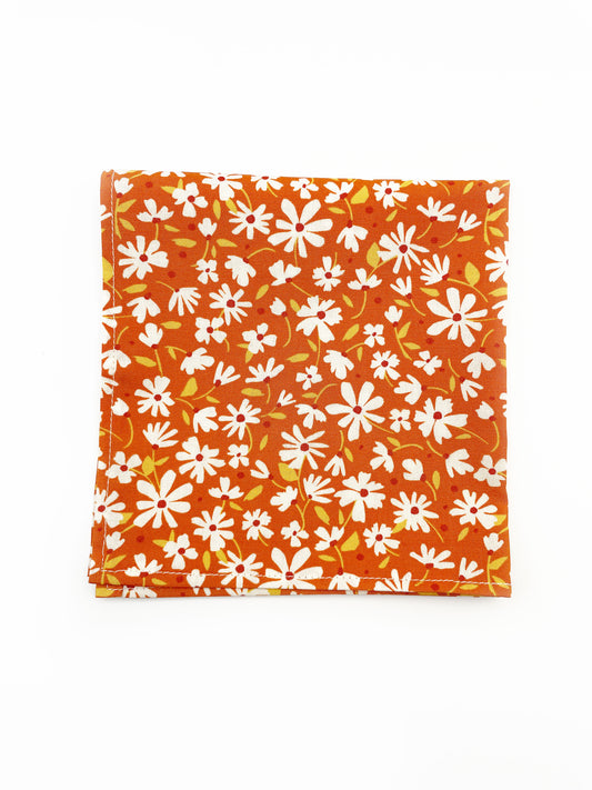 A rust brown floral pocket square with white flowers, showcasing shades of earthy browns and pops of warm peach and blush pink.