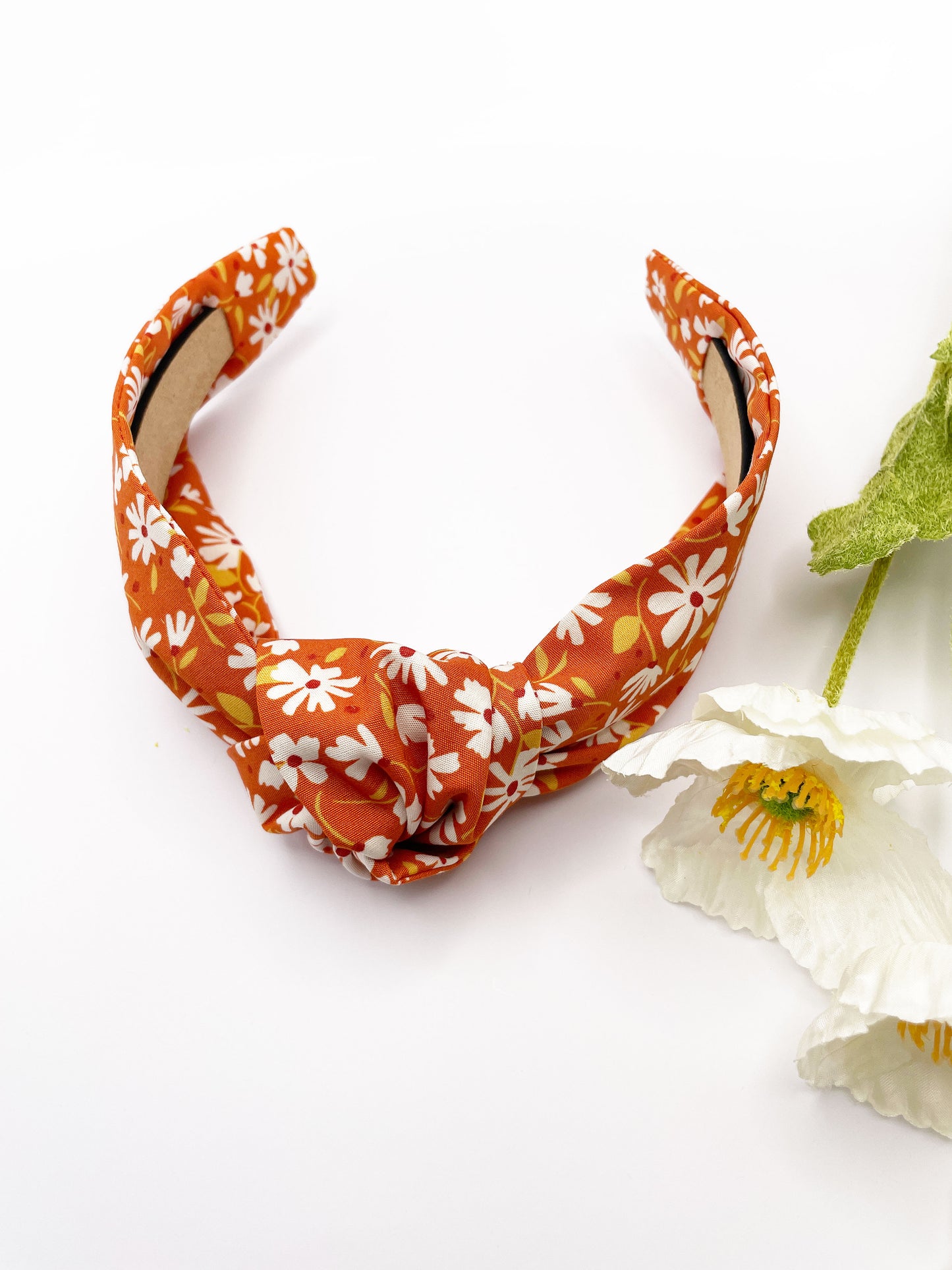 A handmade knotted headband with a warm and earthy color palette, featuring hues of rust, golden brown, and soft neutrals.