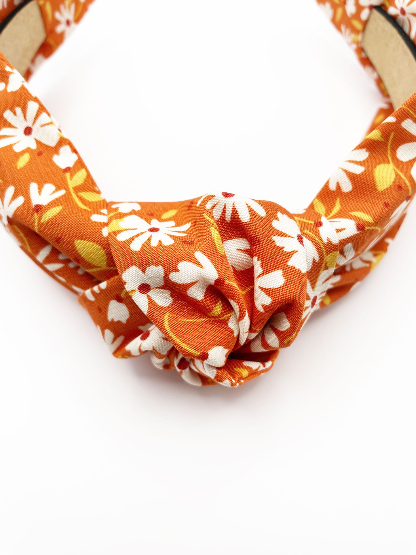 A handmade knotted headband with a warm and earthy color palette, featuring hues of rust, golden brown, and soft neutrals.