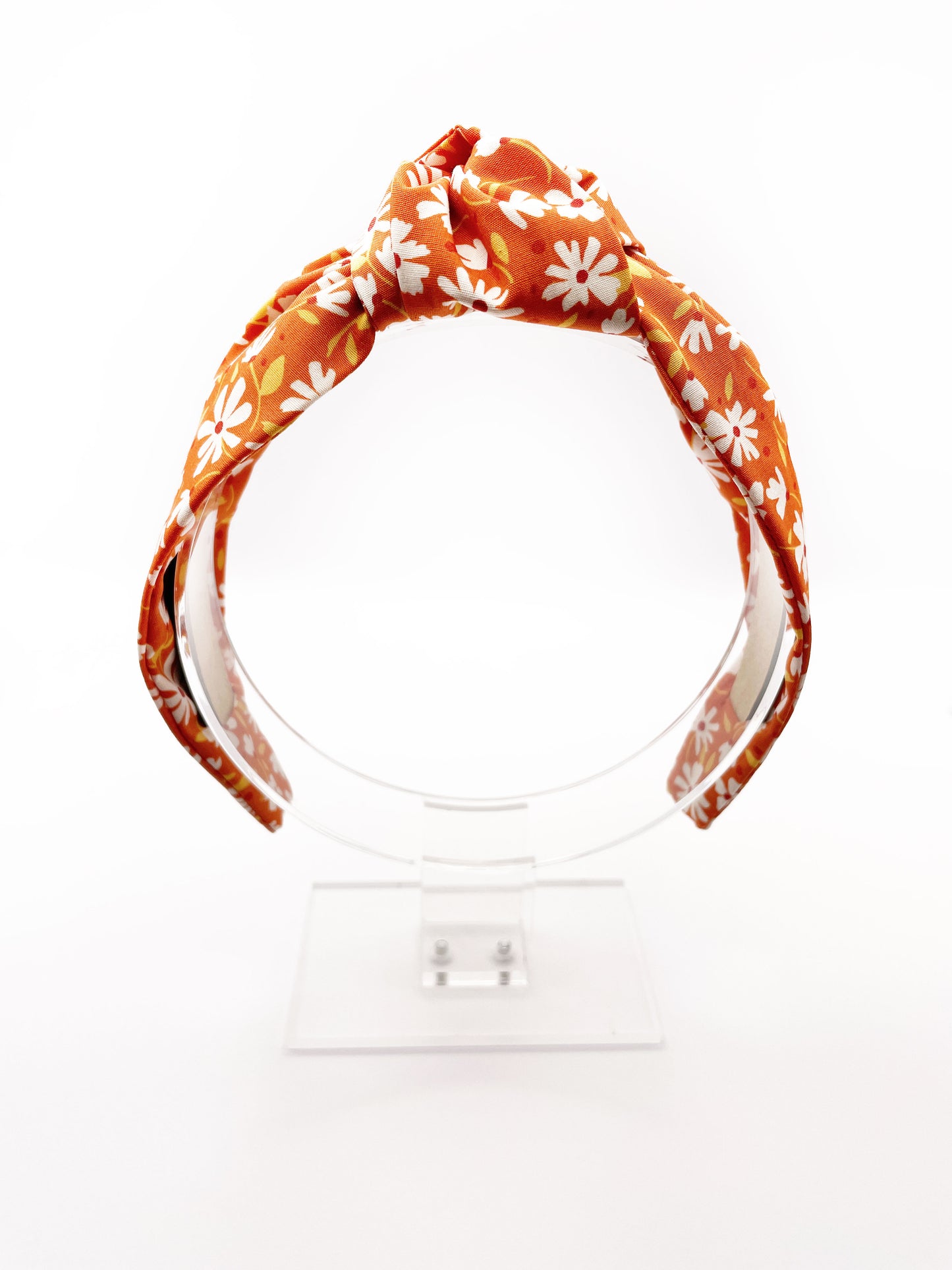 A handmade knotted headband with a warm and earthy color palette, featuring hues of rust, golden brown, and soft neutrals.