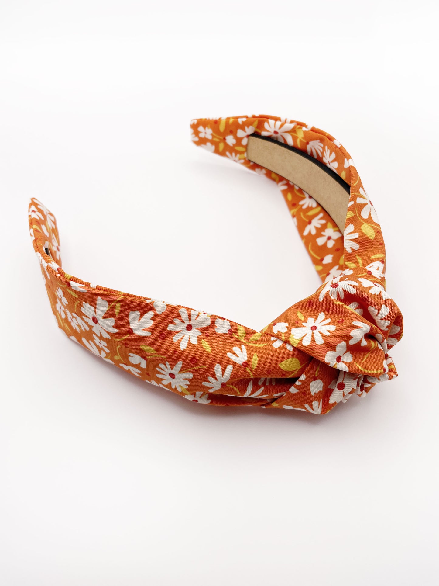 A handmade knotted headband with a warm and earthy color palette, featuring hues of rust, golden brown, and soft neutrals.
