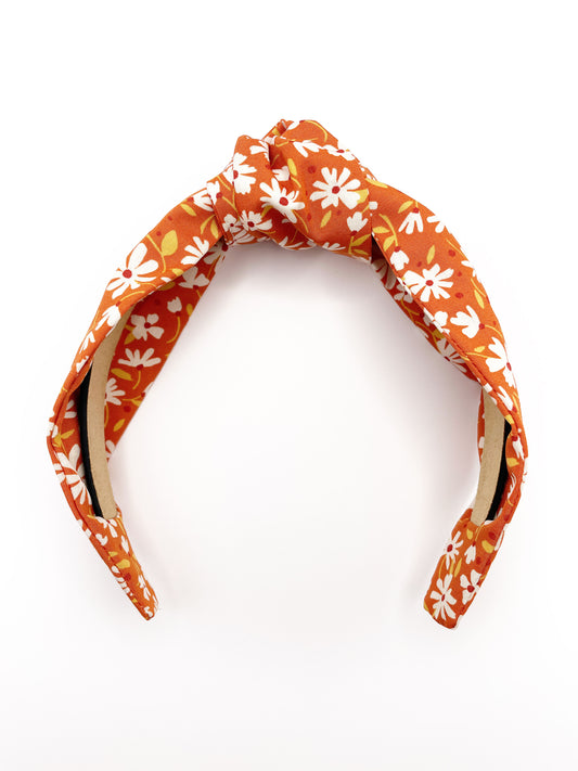 A handmade knotted headband with a warm and earthy color palette, featuring hues of rust, golden brown, and soft neutrals.