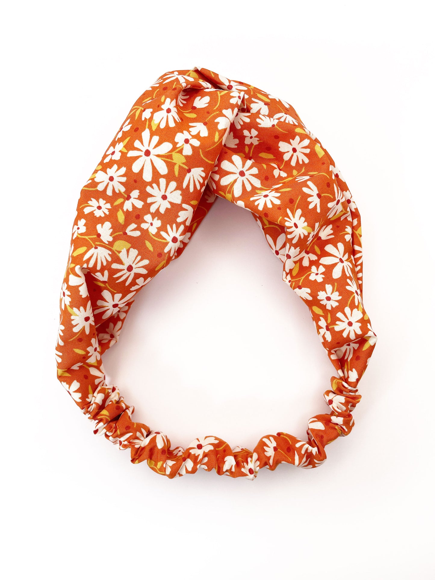 A handmade brown twist headband with off white flowers. The headband has an elastic band on the back.
