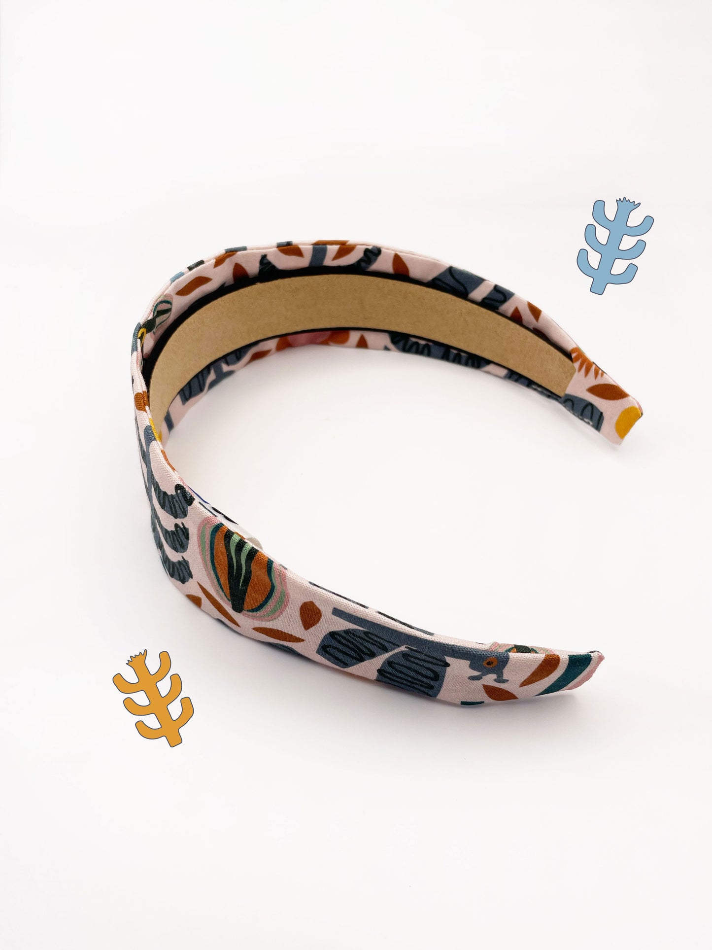 A fabric headband featuring a bold nature-inspired print of bugs, plants, suns, and rainbows.