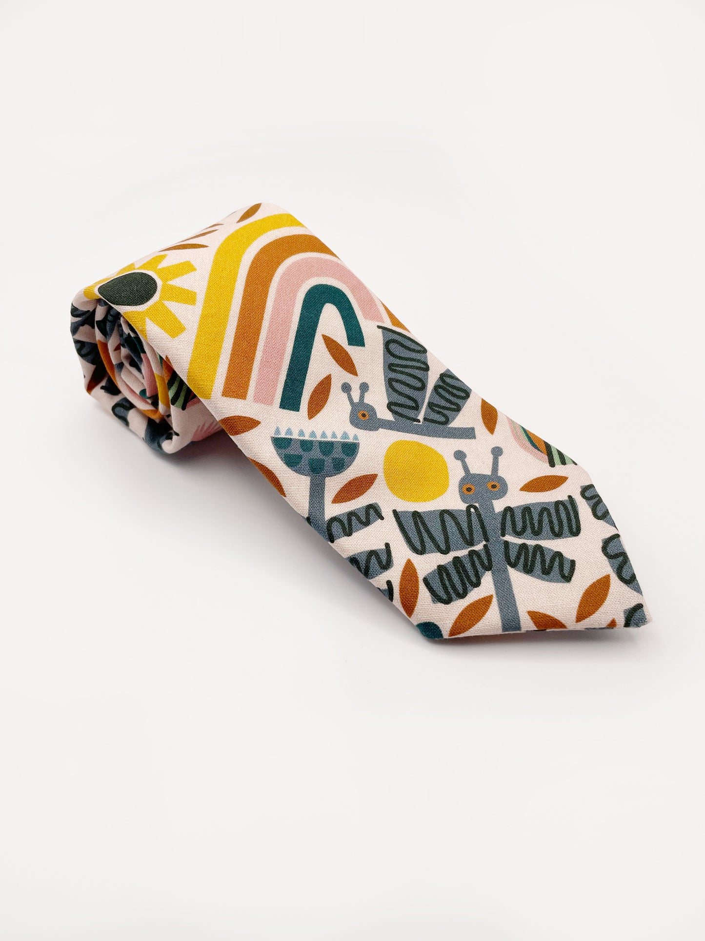 A necktie featuring a bold nature-inspired print of bugs, plants, suns, and rainbows. The color palette includes muted mustard, gentle gray, and soft pastels.