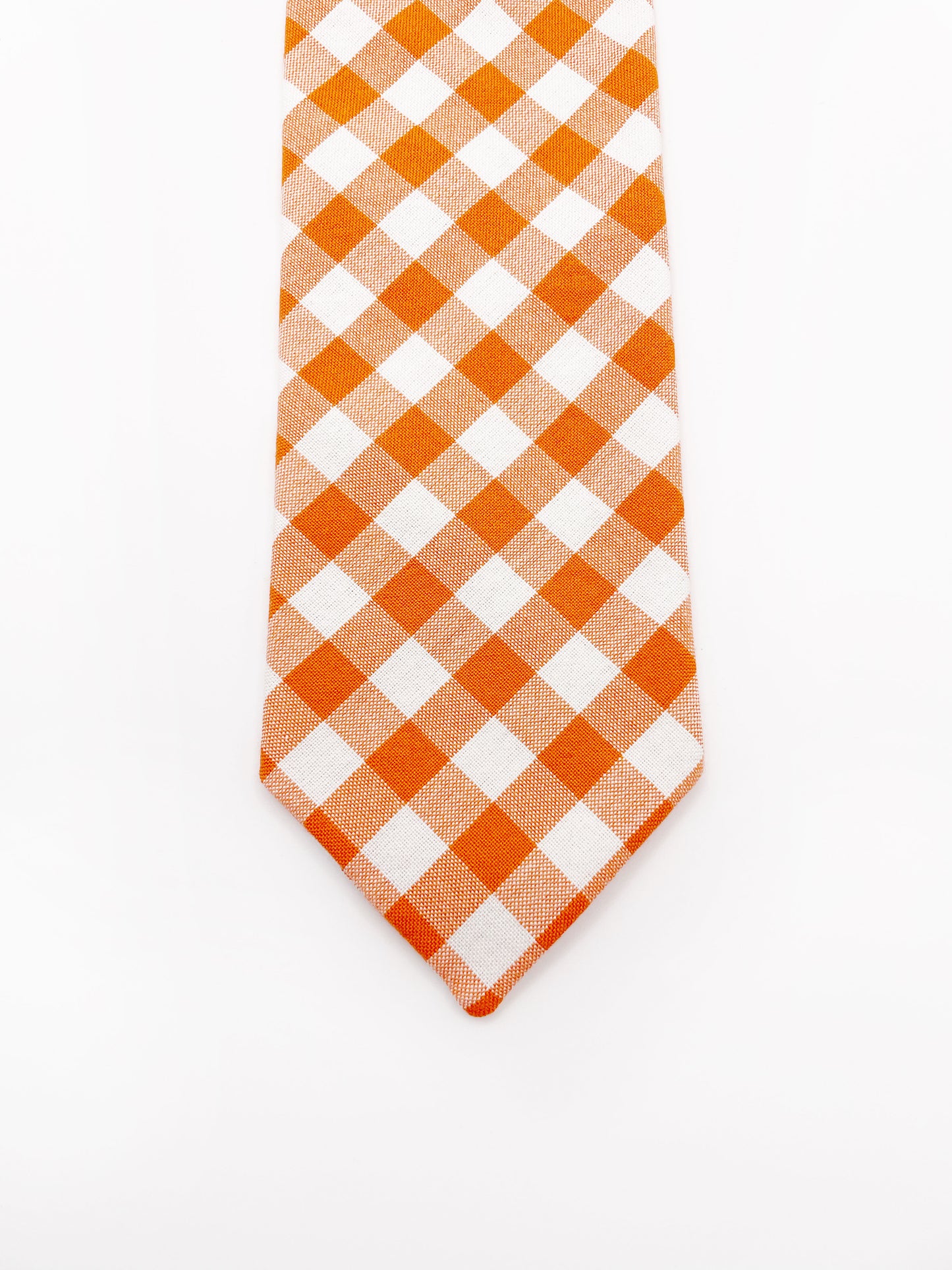 A cotton necktie with an orange and white gingham plaid print.