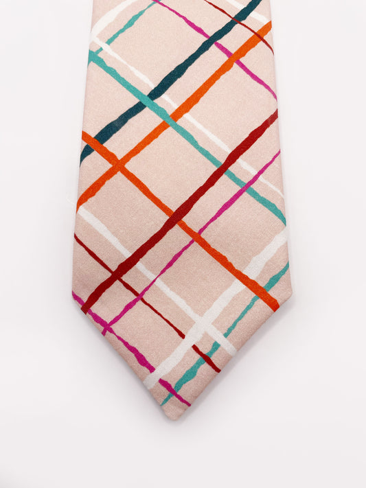 A handmade necktie featuring a colorful and modern plaid design with vibrant shades of pink, red, teal, and orange on a soft pastel background.
