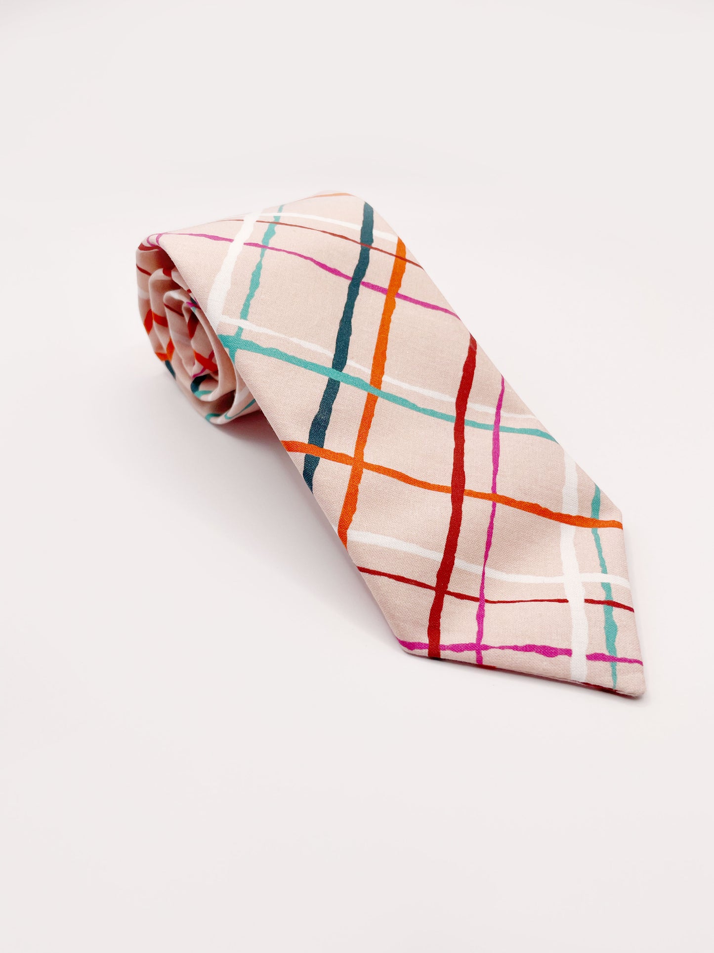 A handmade necktie featuring a colorful and modern plaid design with vibrant shades of pink, red, teal, and orange on a soft pastel background.