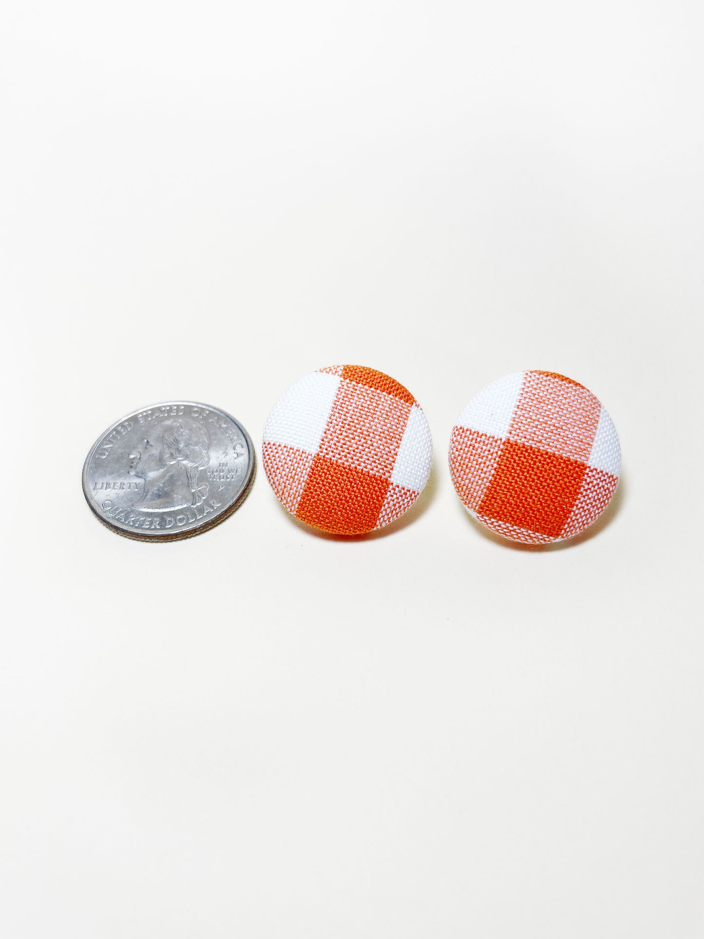 Handmade orange gingham plaid fabric covered post earrings. The earrings are 0.875 inches, roughly the same size as a quarter.