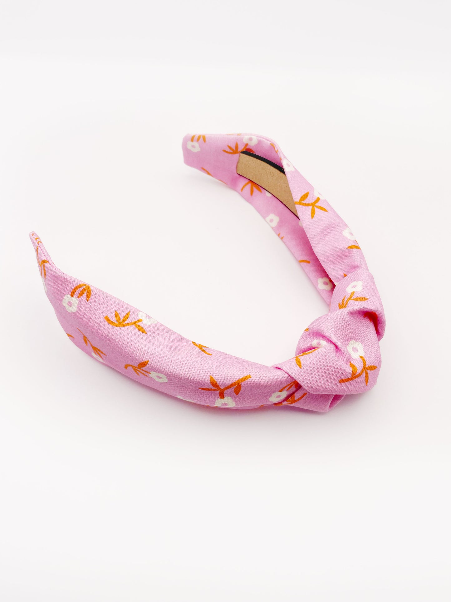 A cheerful pink knotted headband with orange-stemmed flowers.