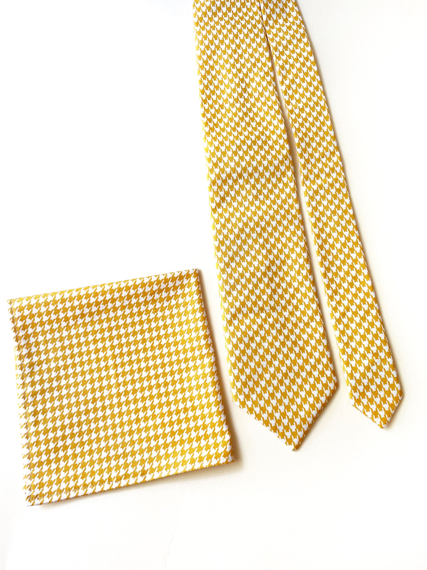 A handmade yellow houndstooth necktie with a matching pocket square.