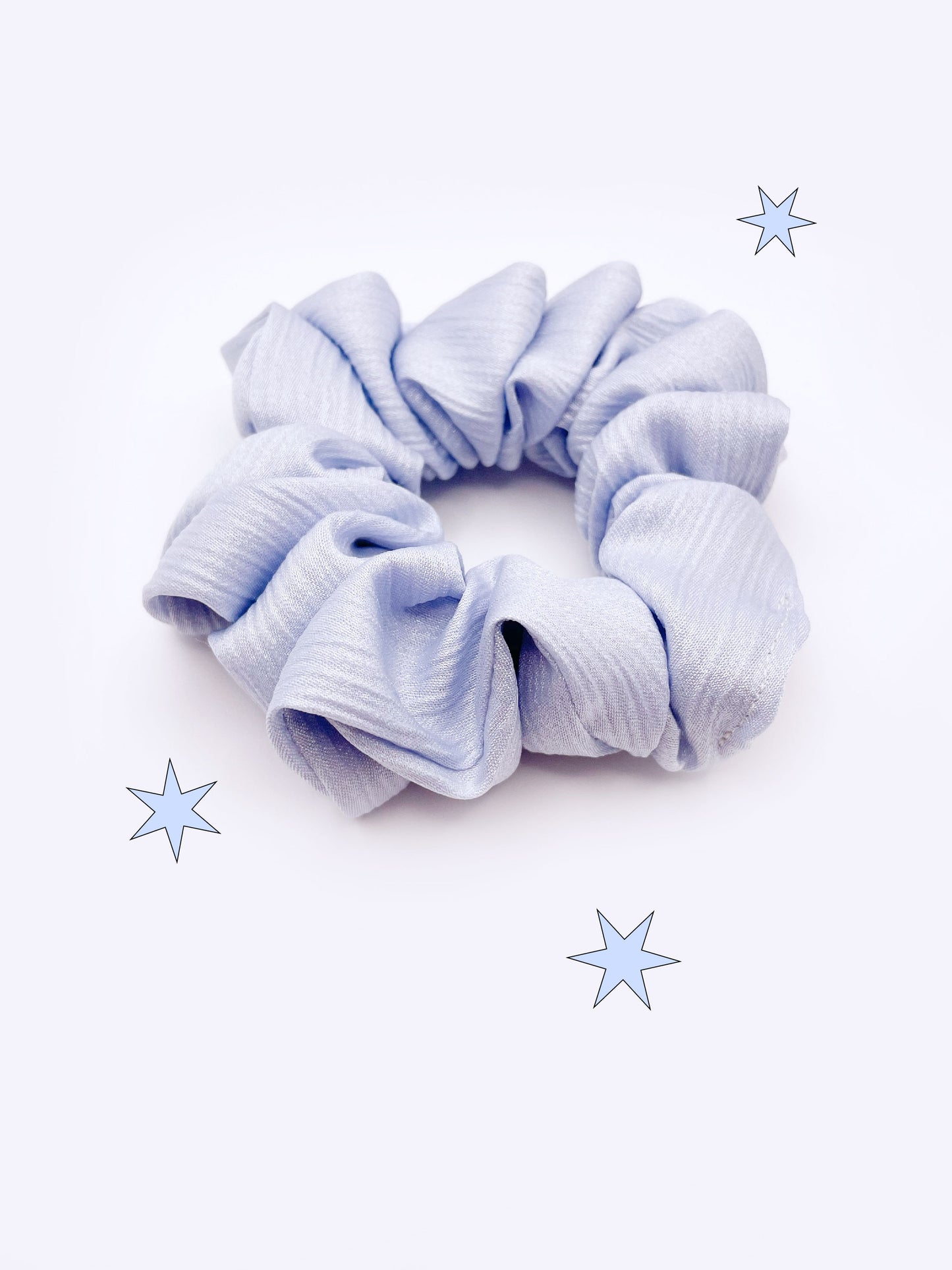 A scrunchie made with a light sky blue crinkle satin fabric.