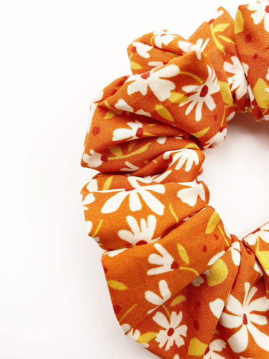 A handmade scrunchie with a warm and earthy color palette, featuring hues of rust, golden brown, and soft neutrals.