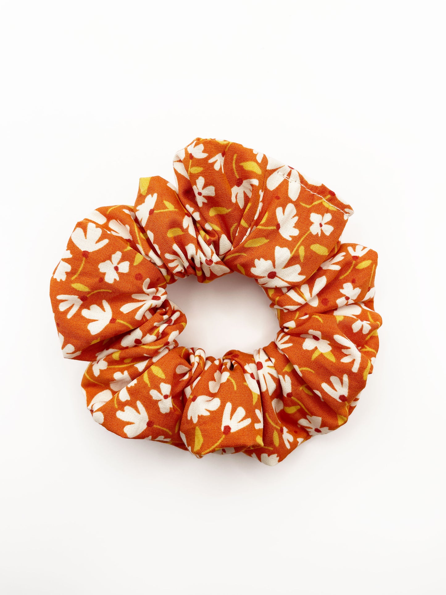 A handmade scrunchie with a warm and earthy color palette, featuring hues of rust, golden brown, and soft neutrals.