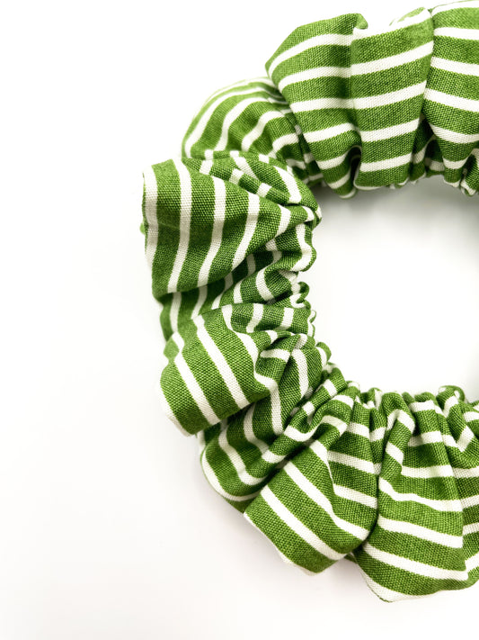 Closeup of a handmade green scrunchie made with cotton fabric featuring white stripes.
