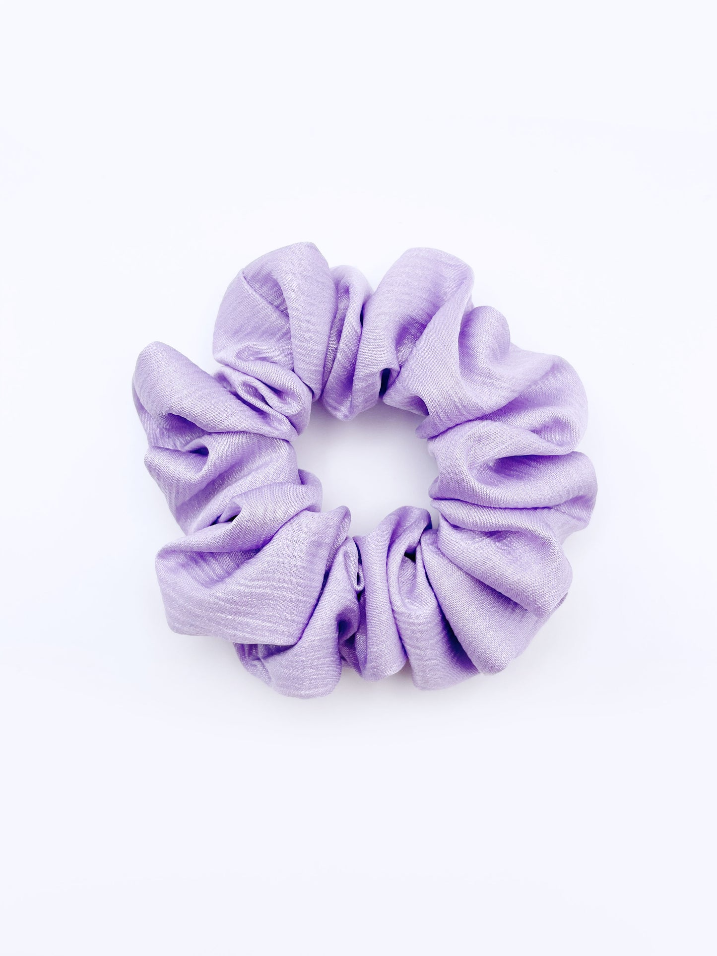 A scrunchie made with a light purple, lavender crinkle satin fabric.