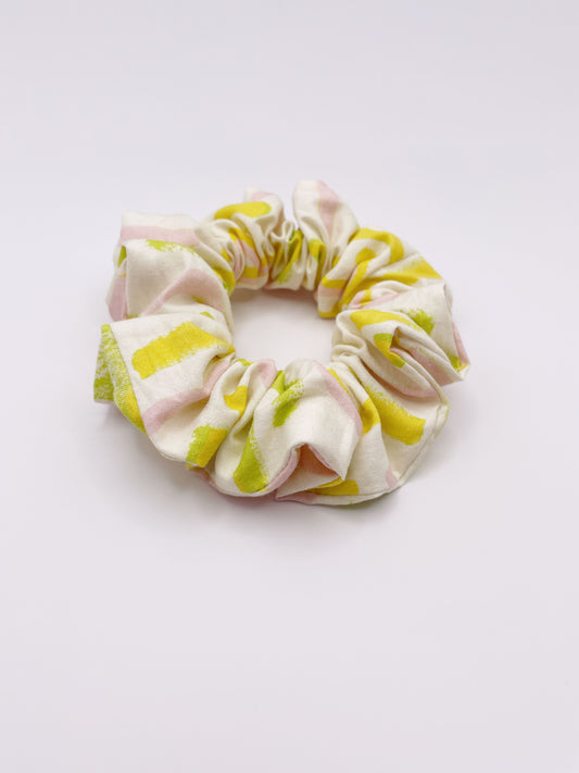 A scrunchie featuring a yellow cactus print with hints of pink and green.