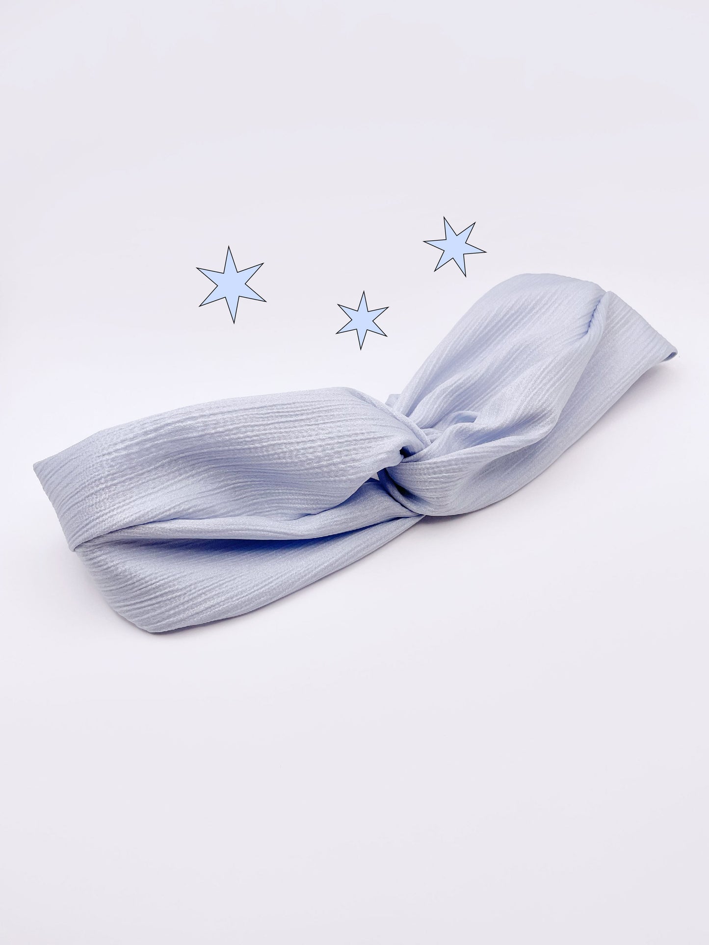A twist headband made with a light sky blue crinkle satin fabric.