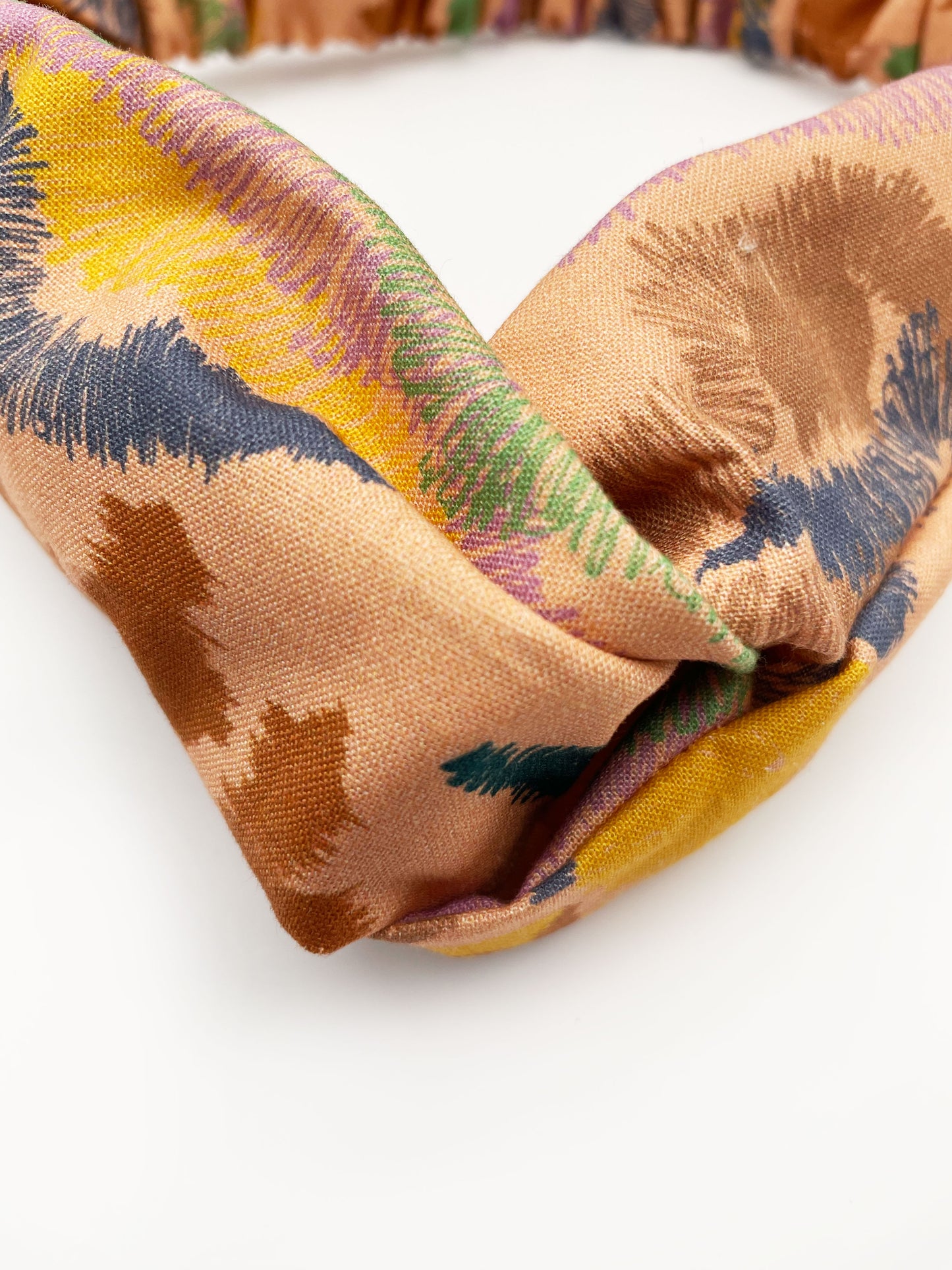 A twist headband crafted from high-quality cotton with an abstract design inspired by the rolling hills and earthy tones of the desert.