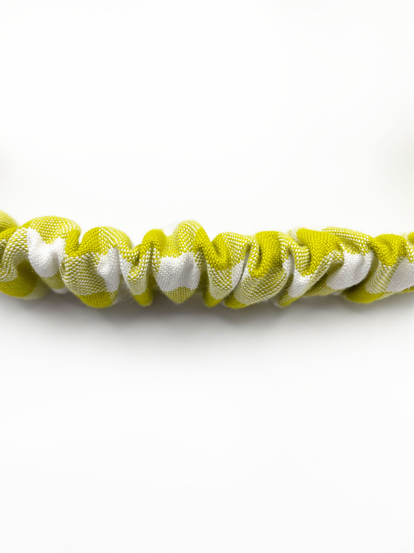 A handmade twist headband with a green and white gingham plaid print. The headband has an elastic band in the back.