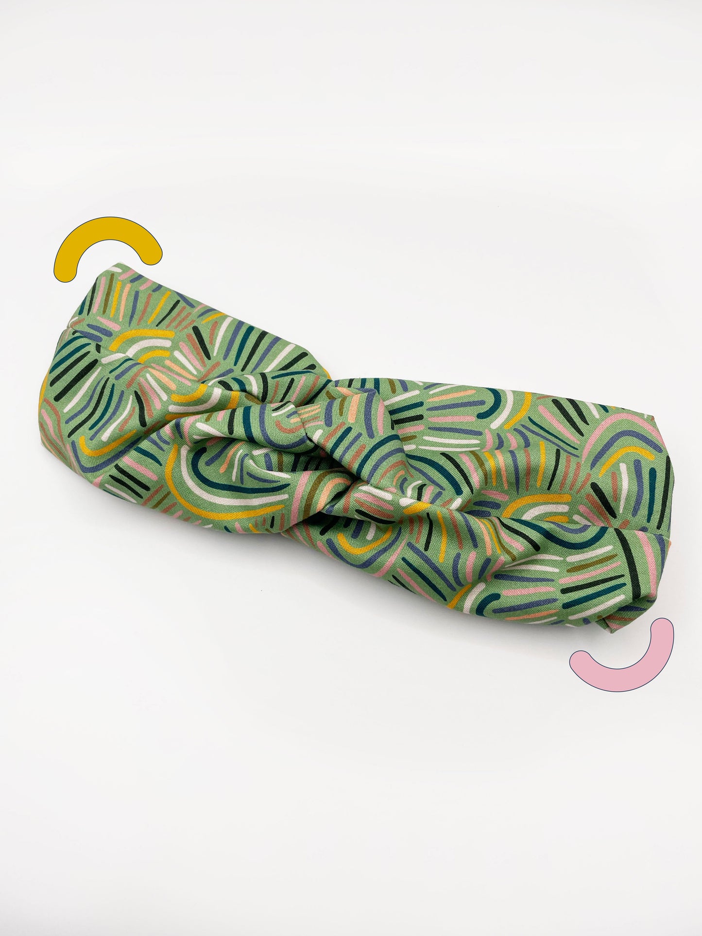 A twist headband made from high-quality cotton with an abstract design inspired by desert rain patterns.