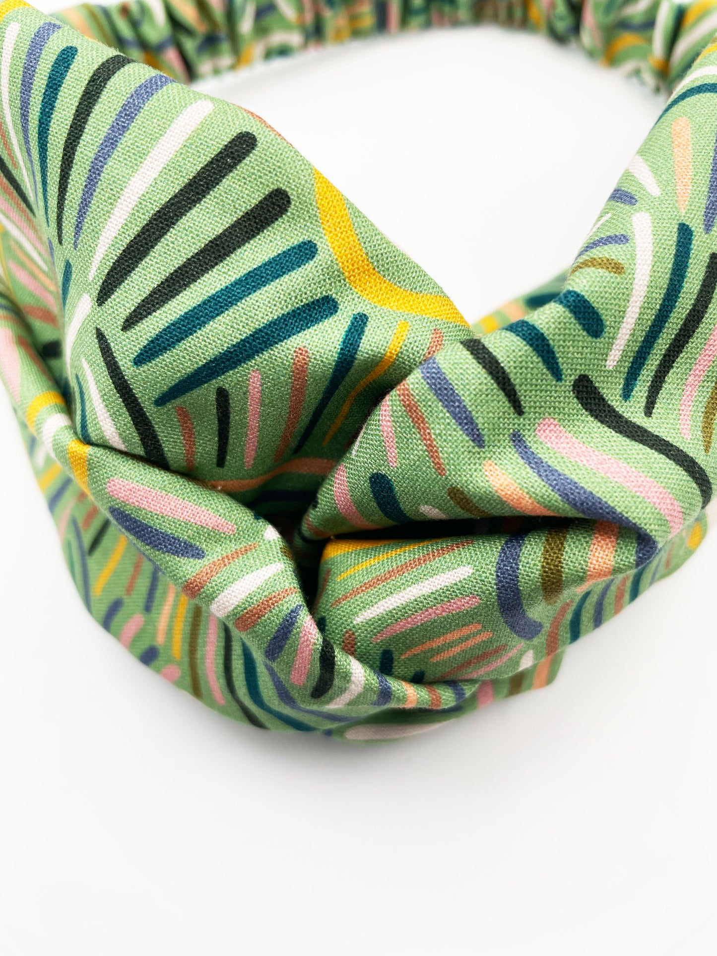 A twist headband made from high-quality cotton with an abstract design inspired by desert rain patterns.