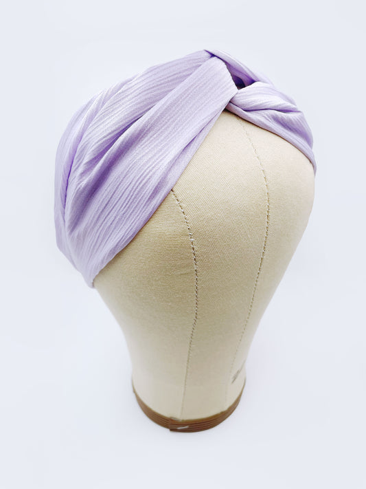 A twist headband made with a light purple, lavender crinkle satin fabric. The headband is displayed on a mannequin head.