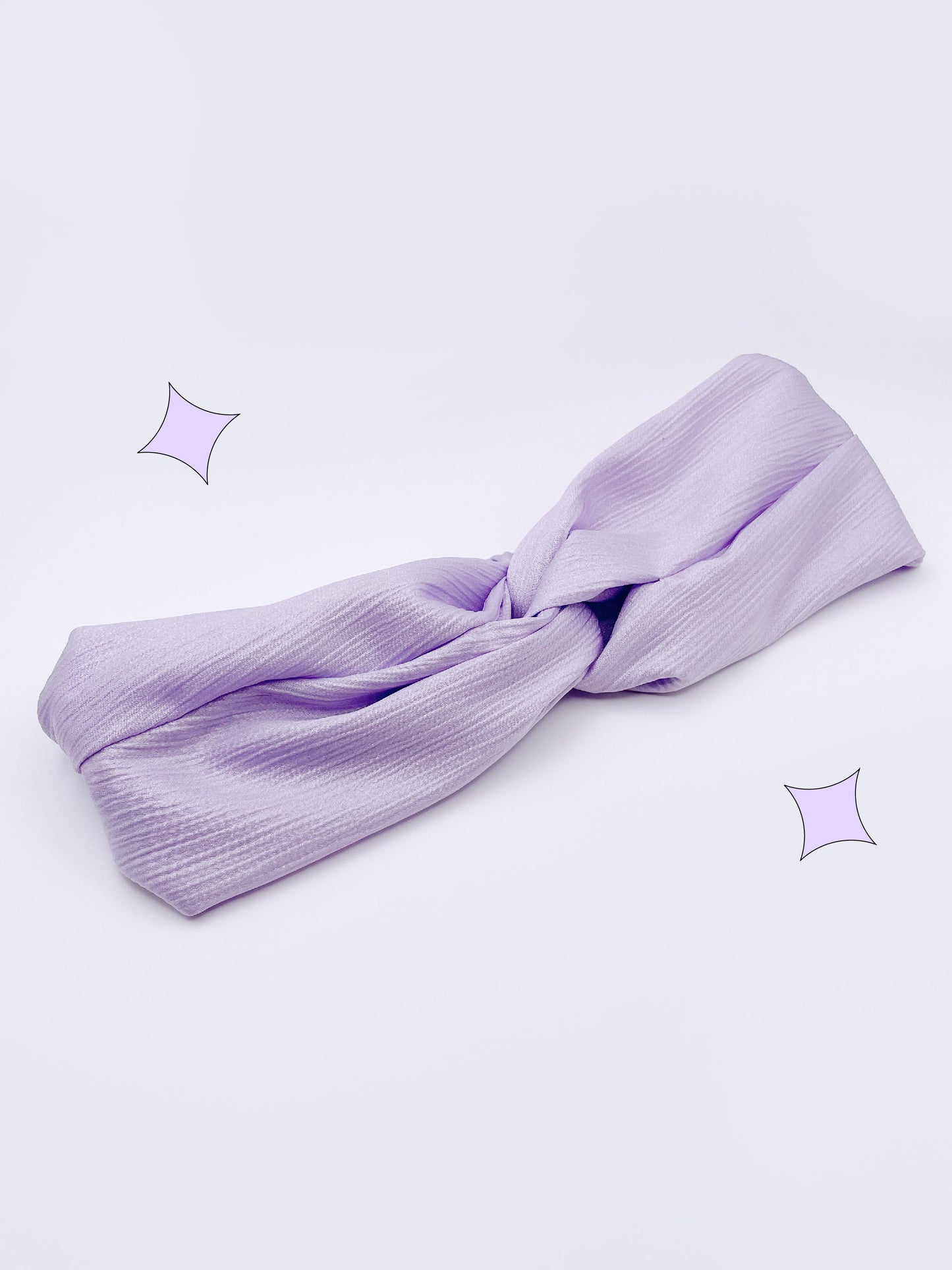 A twist headband made with a light purple, lavender crinkle satin fabric.
