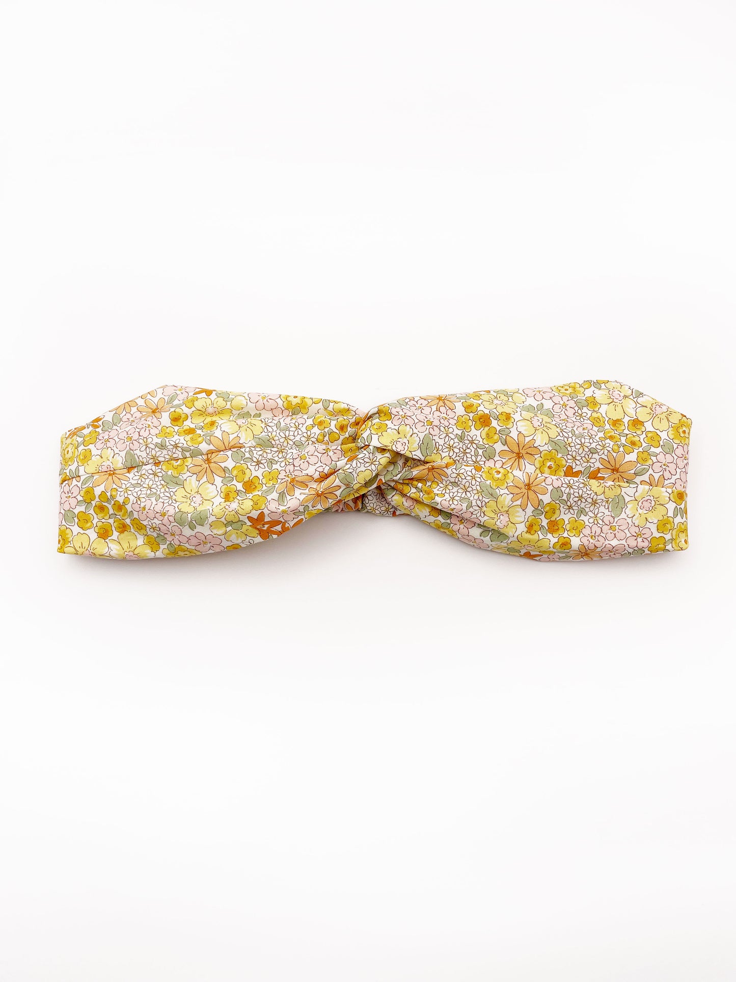 A handmade yellow floral twist headband with an elastic band in the back.