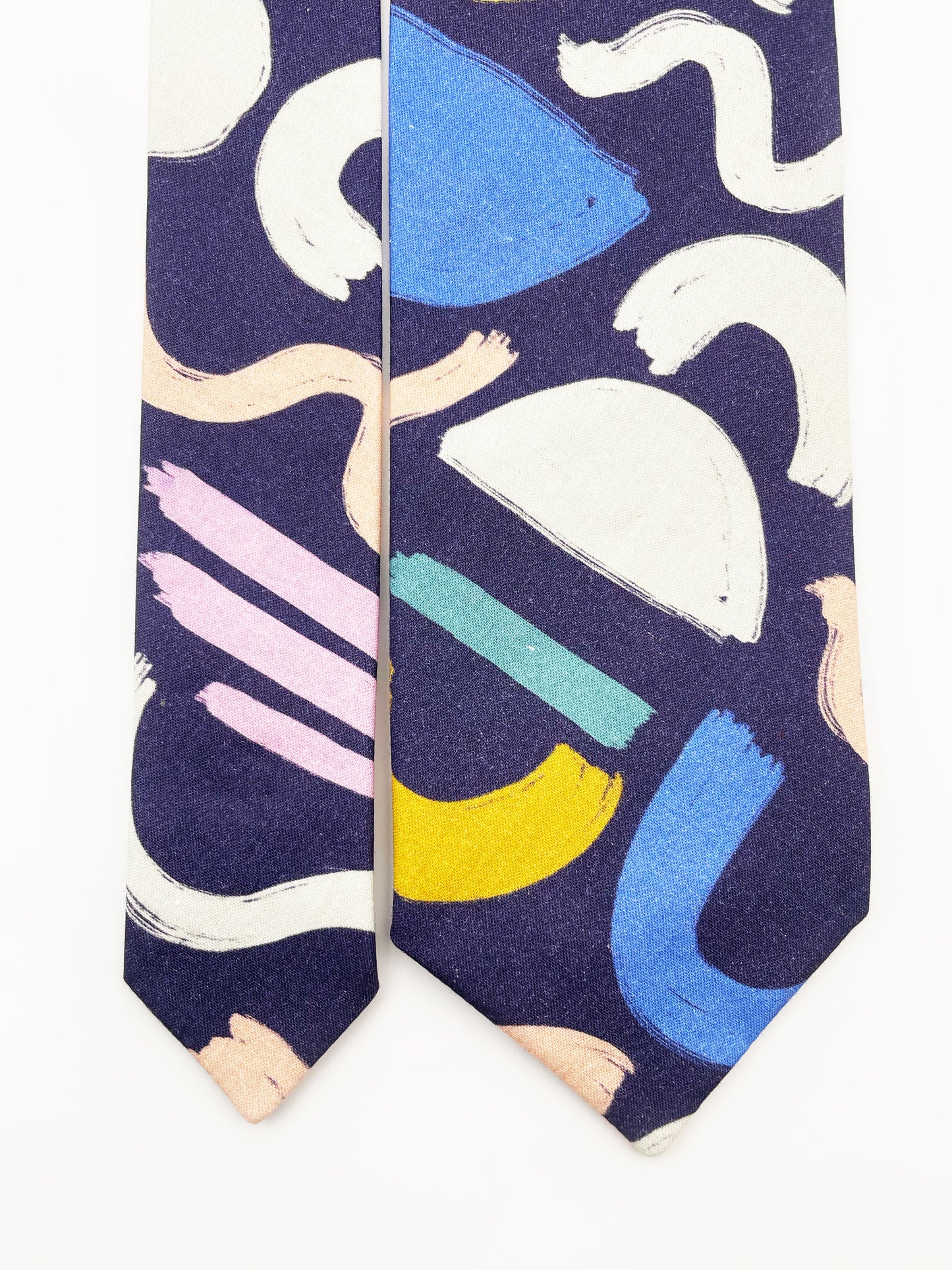A cotton necktie with a colorful abstract print featuring various doodles.