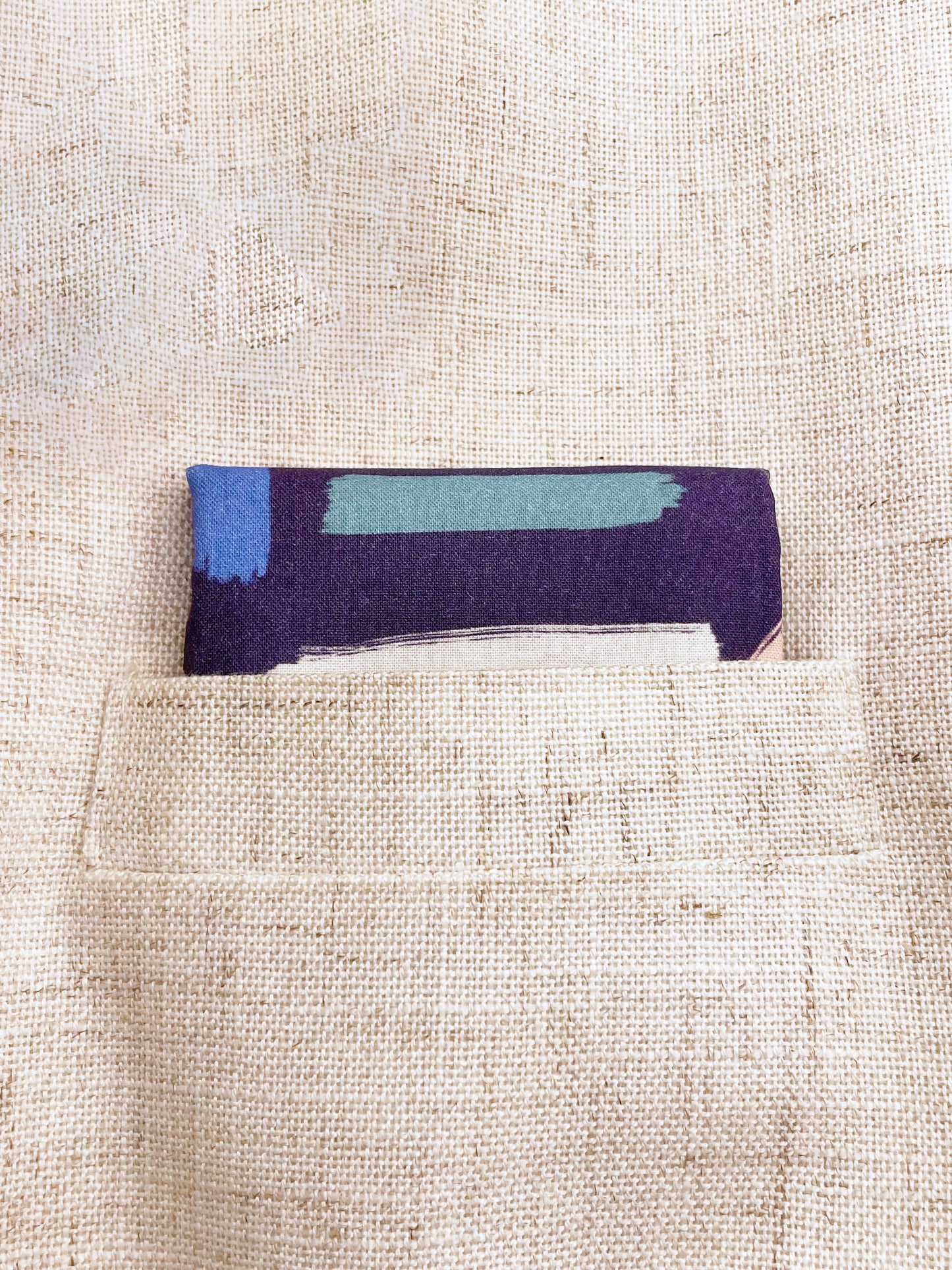 A cotton handmade pocket square with a colorful abstract print featuring various doodles shown in a suit pocket.