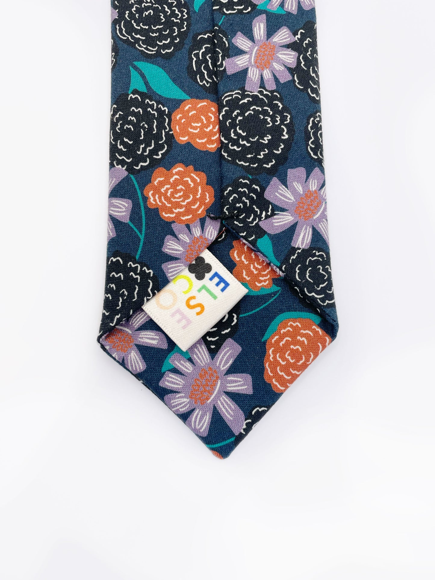 A navy blue necktie with vivid orange, lavender, and black flowers, accented with fresh green leaves.
