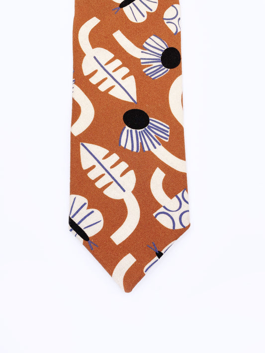 A necktie with an abstract print featuring flowers, leaves, mushrooms, and butterflies on a rich terracotta background. The color palette also consists of cream, black, and blue.