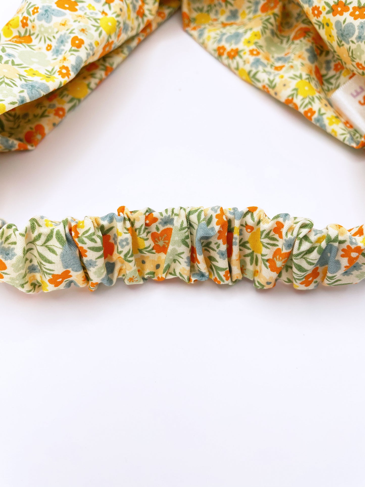 A cotton twist headband with a colorful ditsy floral print. The headband has an elastic band in the back.