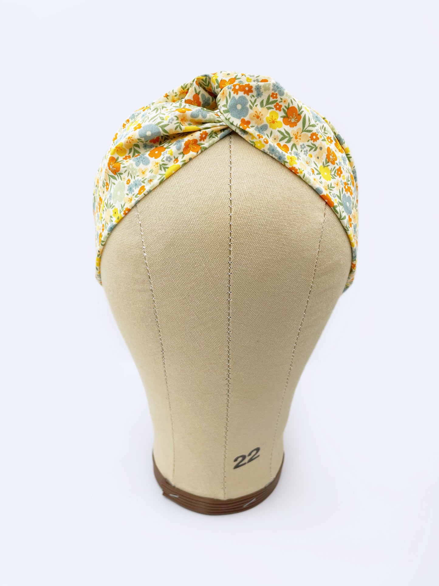A cotton twist headband with a colorful ditsy floral print shown on a mannequin head.
