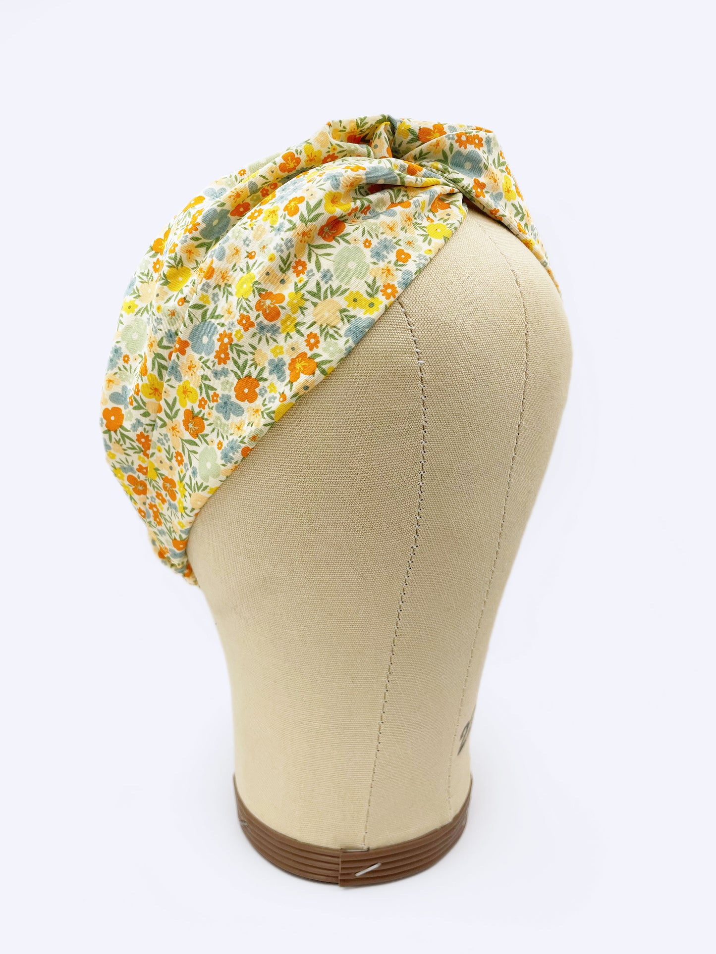 A cotton twist headband with a colorful ditsy floral print shown on a mannequin head.