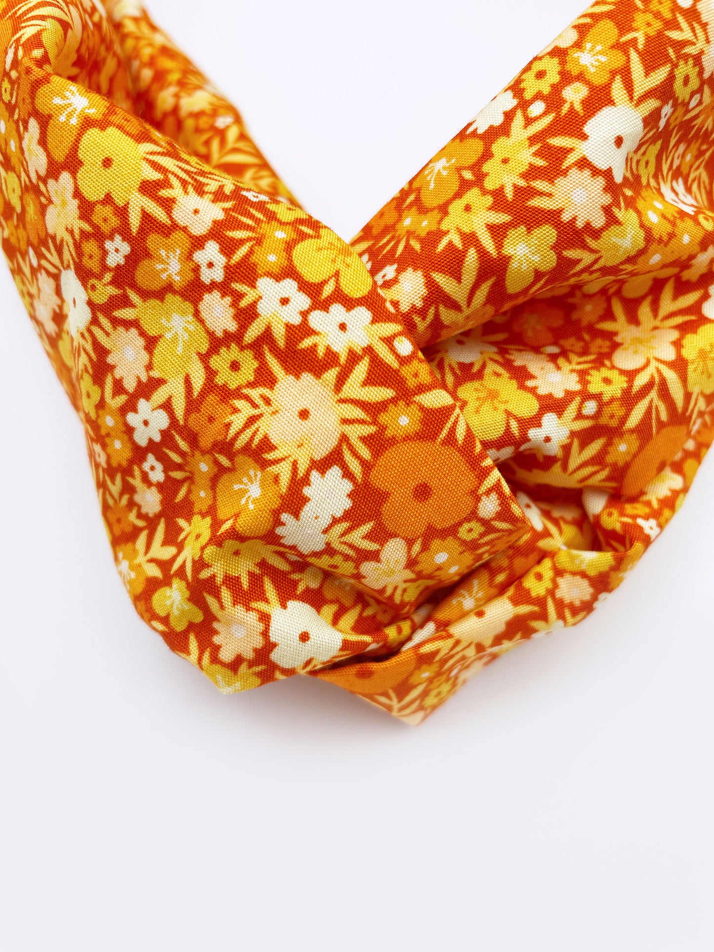 An orange cotton twist headband with a colorful ditsy floral print.
