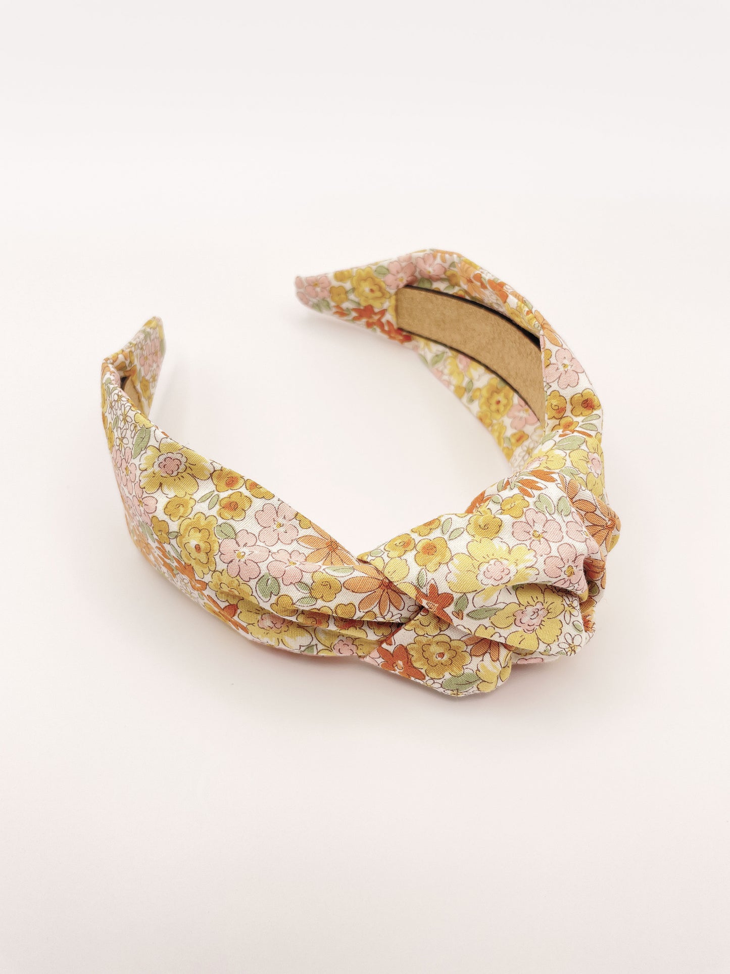 Handmade knotted headband with yellow flowers against an off white background