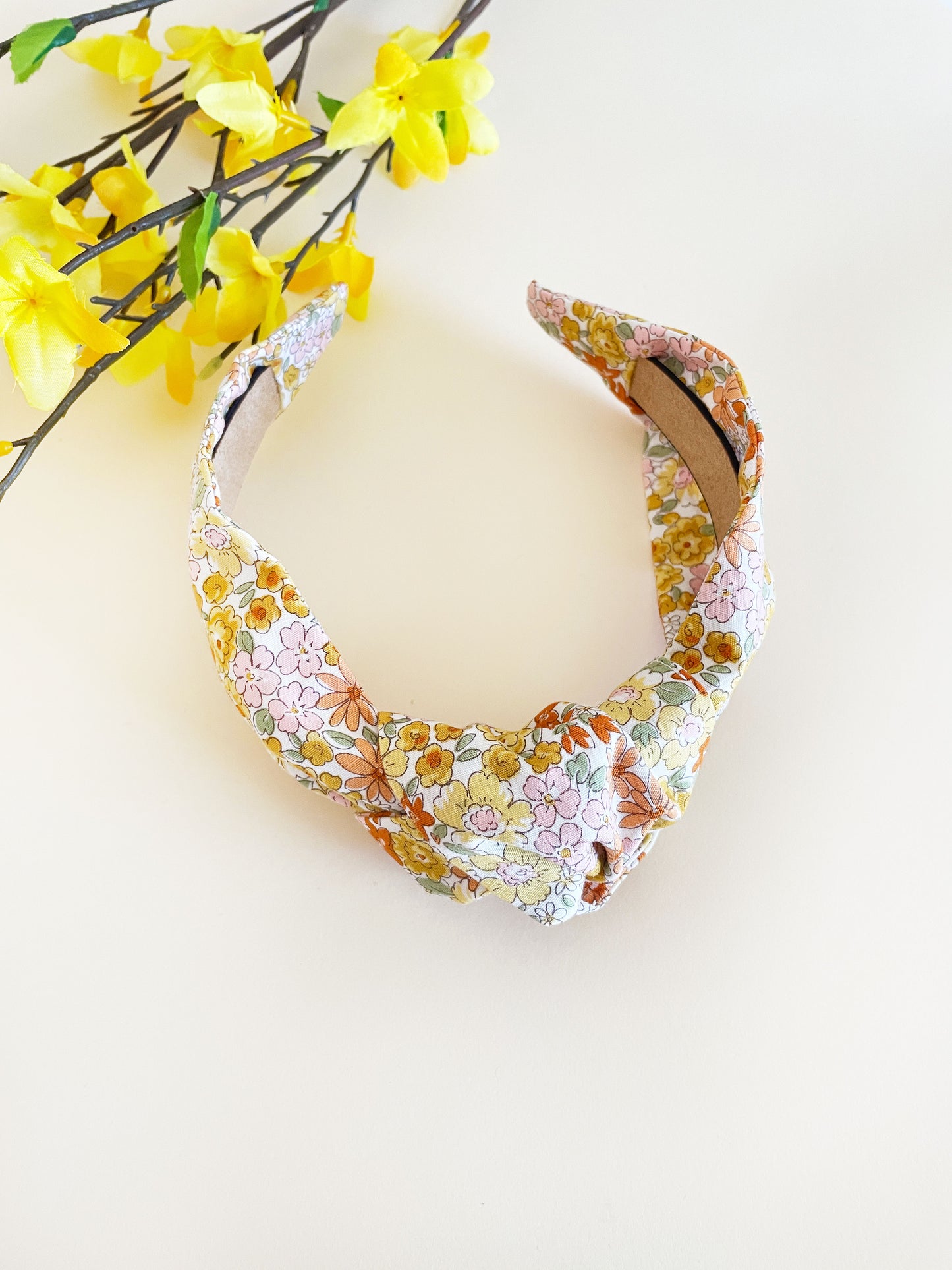 Handmade knotted headband with yellow flowers against an off white background
