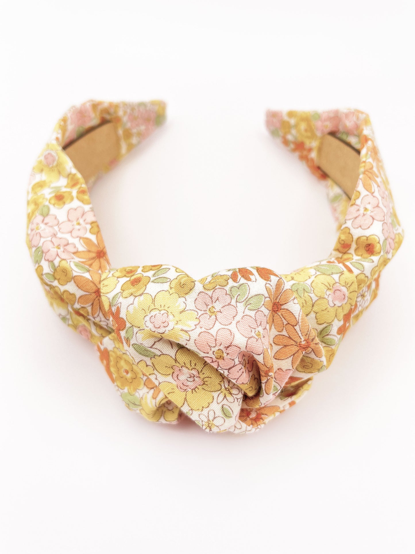 Handmade knotted headband with yellow flowers against an off white background