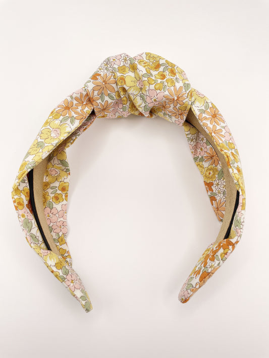 Handmade knotted headband with yellow flowers against an off white background
