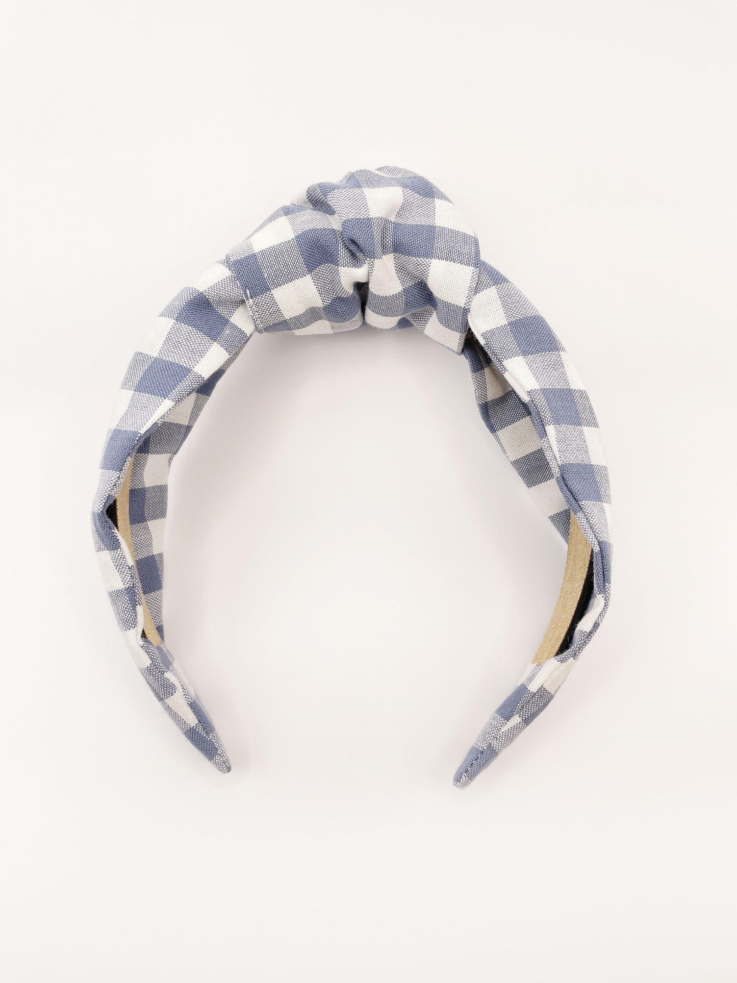 A handmade slate blue gingham plaid knotted headband against an off white background.