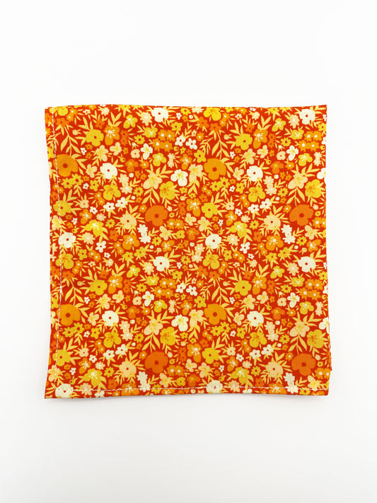 A handmade pocket square featuring vibrant orange and yellow flowers.